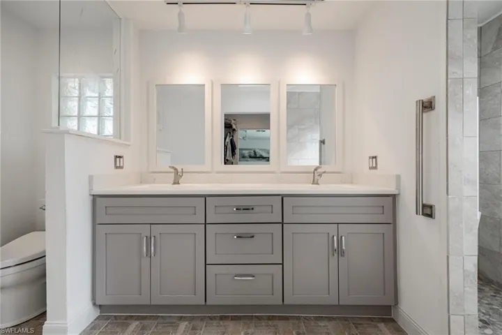 Bathroom featuring double vanity, toilet, and rail lighting