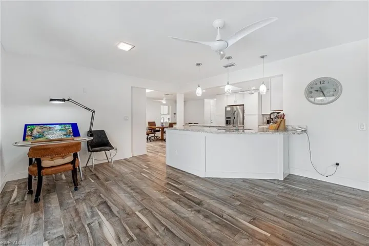 Kitchen with ceiling fan, kitchen peninsula, stainless steel fridge with ice dispenser, white cabinets, and wood-type flooring