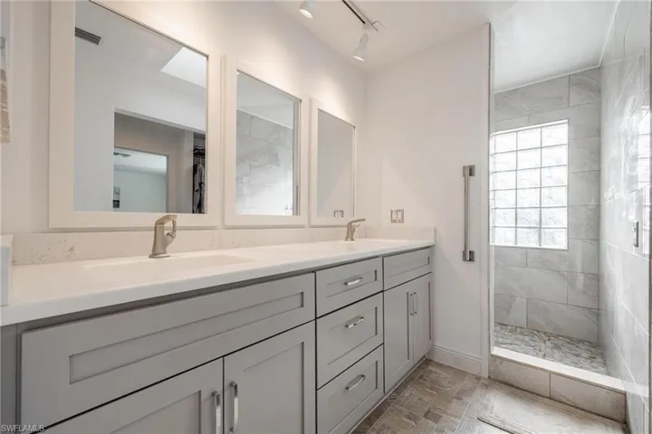 Bathroom with double vanity, tiled shower, and tile patterned floors