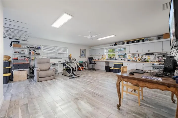 Workshop area featuring ceiling fan and light wood-type laminate flooring