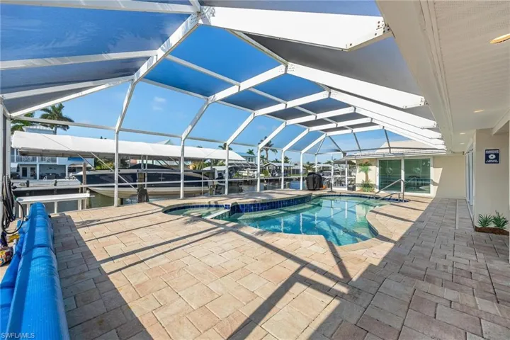 View of pool featuring glass enclosure, a jacuzzi, and a patio area