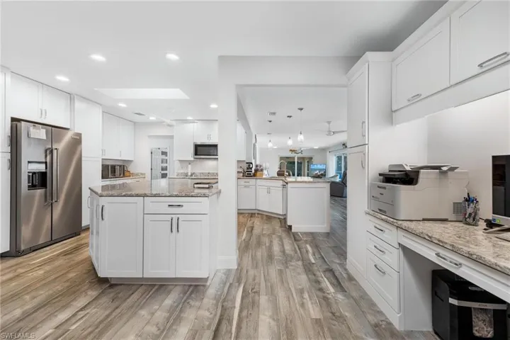Kitchen featuring stainless steel appliances, white cabinetry, a skylight, and light hardwood / wood-style floors
