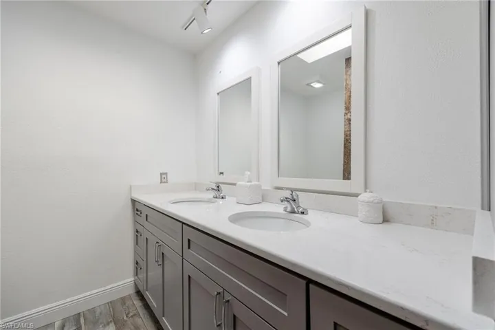 Bathroom with double vanity, rail lighting, and wood-type flooring