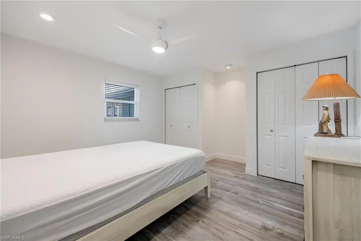Bedroom featuring ceiling fan, light hardwood / wood-style flooring, and two closets