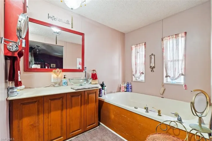 Full bathroom with a textured ceiling, vanity, and a garden tub