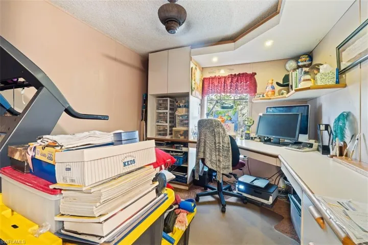Office with a textured ceiling, recessed lighting, and dark colored carpet