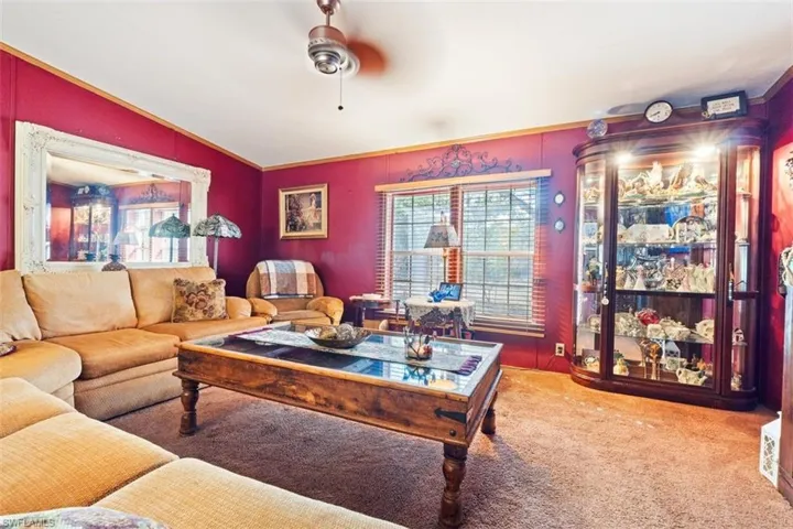 Living area with lofted ceiling, carpet, and a ceiling fan