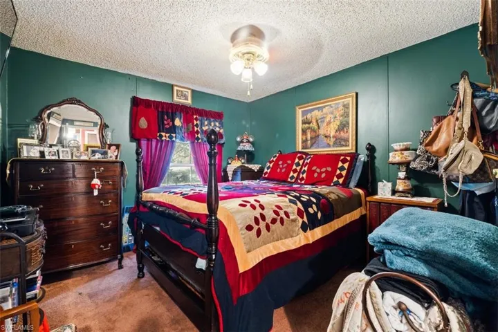 Carpeted bedroom with a ceiling fan and a textured ceiling