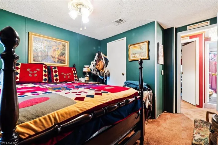 Bedroom featuring a textured ceiling, light colored carpet, and ceiling fan