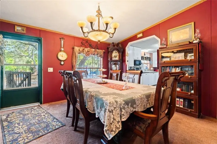 Dining area featuring hanging lights, carpet flooring, and crown molding