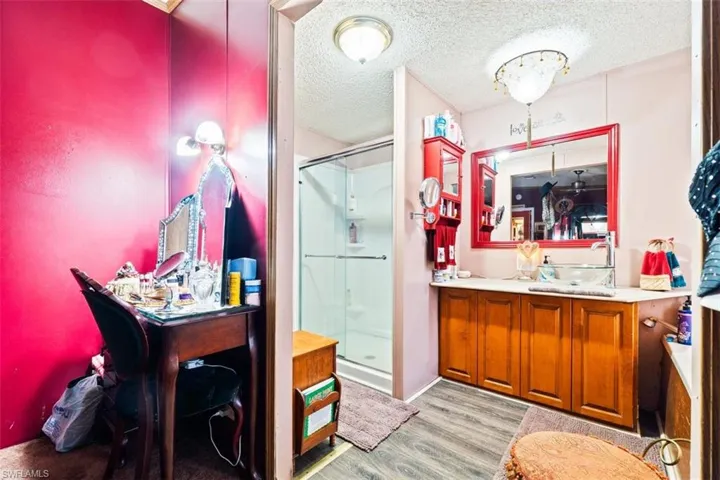 Bathroom featuring a textured ceiling, a stall shower, vanity, and light wood-style floors