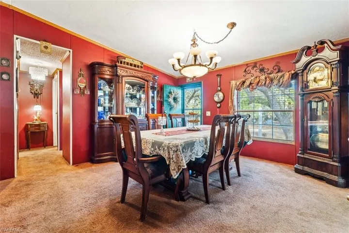 Dining space featuring light carpet, suspended lighting, vaulted ceiling, and crown molding