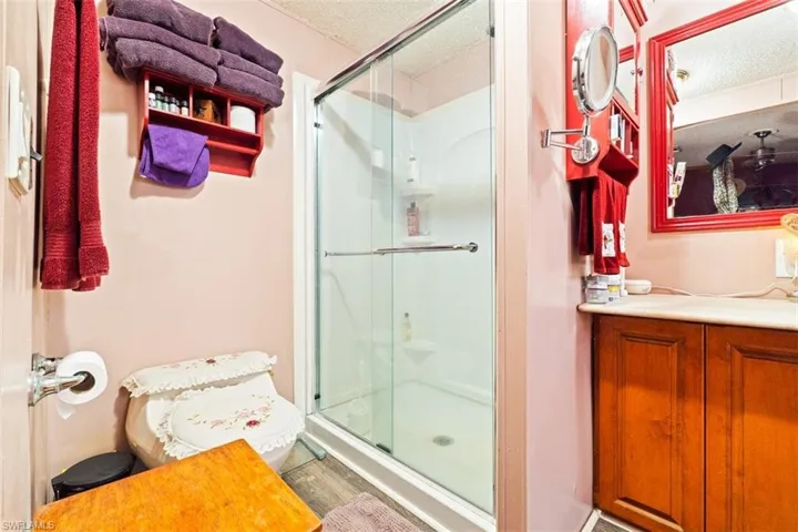 Bathroom featuring a textured ceiling, a shower stall, and vanity
