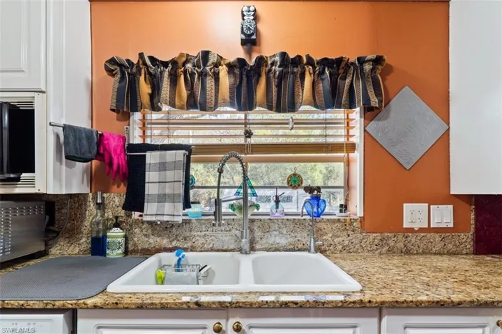 Kitchen featuring white cabinetry and light stone counters