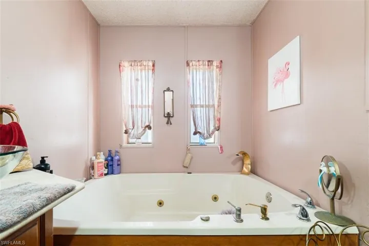 Full bath featuring a whirlpool tub, a textured ceiling, and vanity