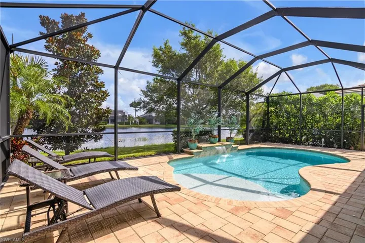 View of swimming pool with a lanai, pool water feature, a patio, and a tranquil lake view