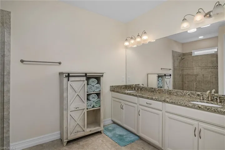 Master bathroom featuring tile patterned flooring, a tile shower, and vanity