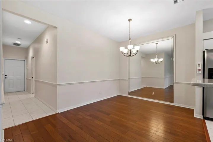 Unfurnished dining area featuring a chandelier, hardwood / wood-style floors, baseboards, and visible vents