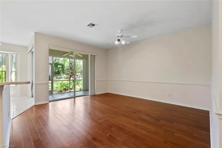 Empty room with hardwood / wood-style floors, visible vents, baseboards, and a ceiling fan