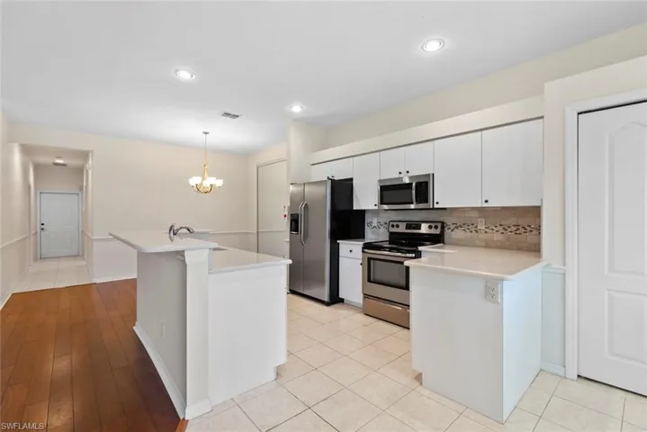 Kitchen with tasteful backsplash, white cabinetry, appliances with stainless steel finishes, a sink, and light countertops
