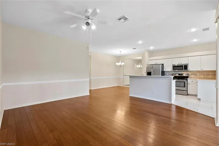 Unfurnished living room featuring recessed lighting, light wood-type flooring, visible vents, and ceiling fan with notable chandelier
