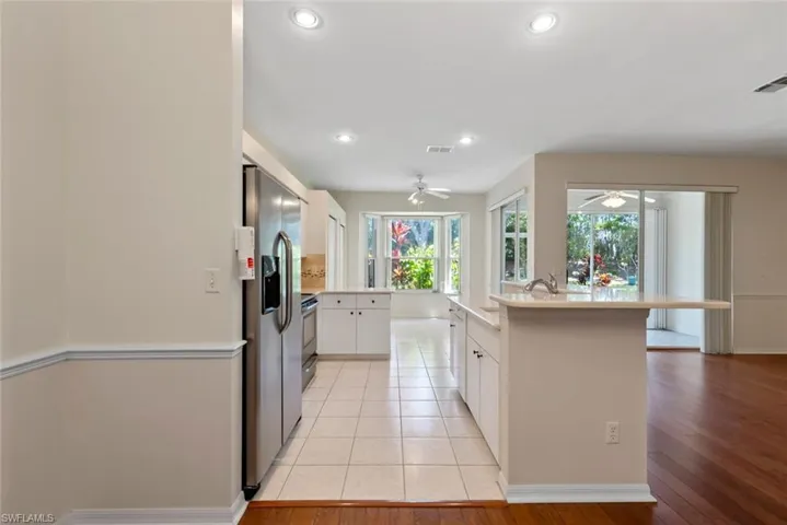 Kitchen with stainless steel fridge with ice dispenser, visible vents, light countertops, a ceiling fan, and white cabinetry