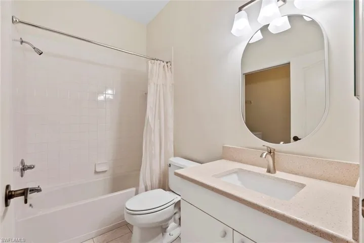 Full bathroom featuring shower / bath combo, tile patterned flooring, toilet, and vanity