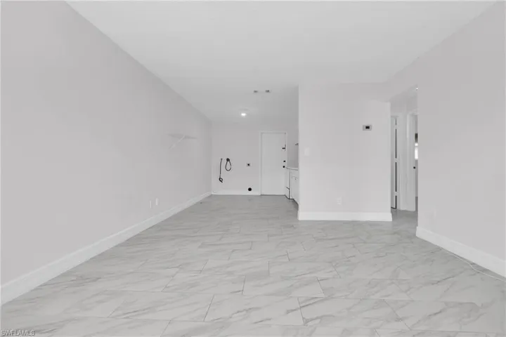 Empty room featuring light marble finish flooring and baseboards