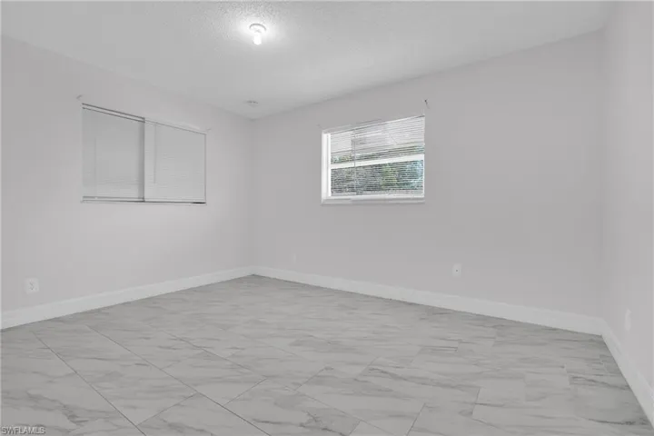 Unfurnished room with light marble finish flooring and a textured ceiling