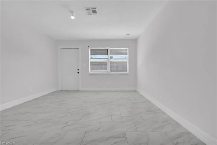 Spare room featuring baseboards and light marble finish floors