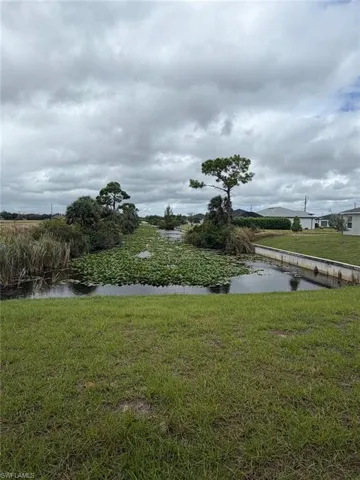 Waterfront parcel featuring a concrete bulkhead, grass lawn, and mature trees