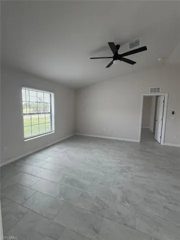 Vaulted ceilings, large-format tile flooring, matte black ceiling fan, and grid-patterned window