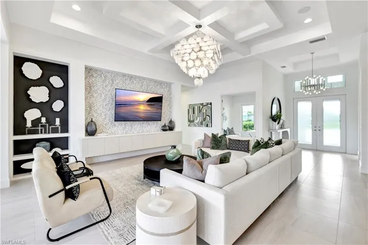 Living room featuring a chandelier, french doors, coffered ceiling, beamed ceiling, and a towering ceiling