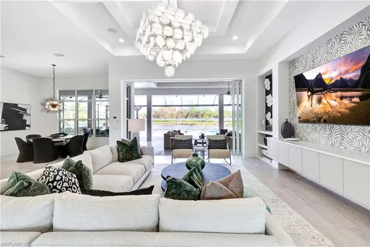 Living room featuring a chandelier, recessed lighting, a raised ceiling, and built in features