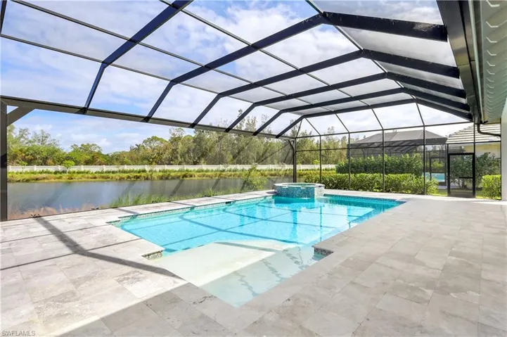 View of pool with a sunroom, a lanai, a pool with connected hot tub, a patio area, and a water view