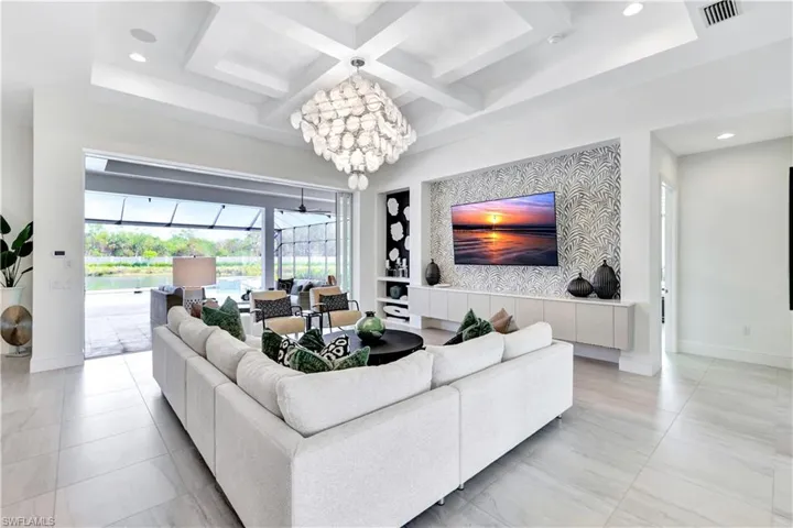 Living area with a sunroom, a chandelier, recessed lighting, coffered ceiling, and beam ceiling