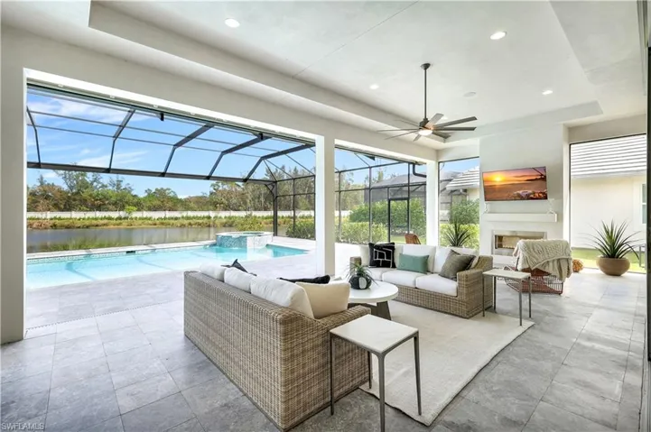View of patio with a ceiling fan, a pool with connected hot tub, a sunroom, glass enclosure, and an outdoor living space with a fireplace