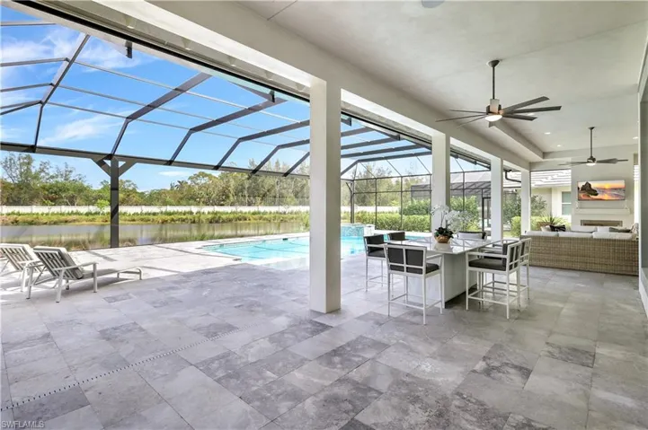 Swimming pool featuring a patio area, a sunroom, a lanai, a water view, and an outdoor living space