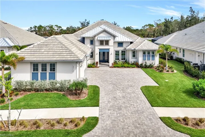 View of front facade with a front yard, driveway, stucco siding, and a tiled roof