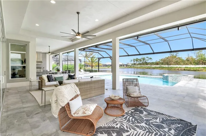 View of patio / terrace with a sunroom, a ceiling fan, a water view, glass enclosure, and a pool with connected hot tub