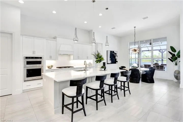 Kitchen with white cabinetry, recessed lighting, a kitchen breakfast bar, light stone counters, and hanging light fixtures