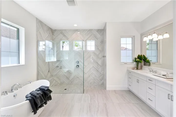 Full bath with vanity, a soaking tub, a stall shower, and recessed lighting