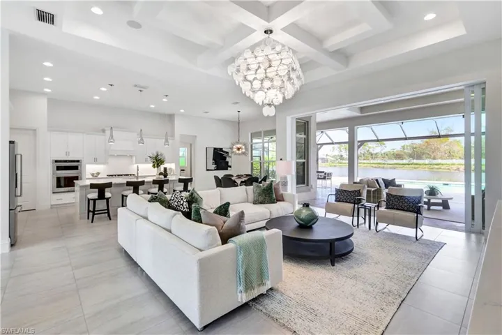 Living room with coffered ceiling, recessed lighting, beam ceiling, a chandelier, and a water view