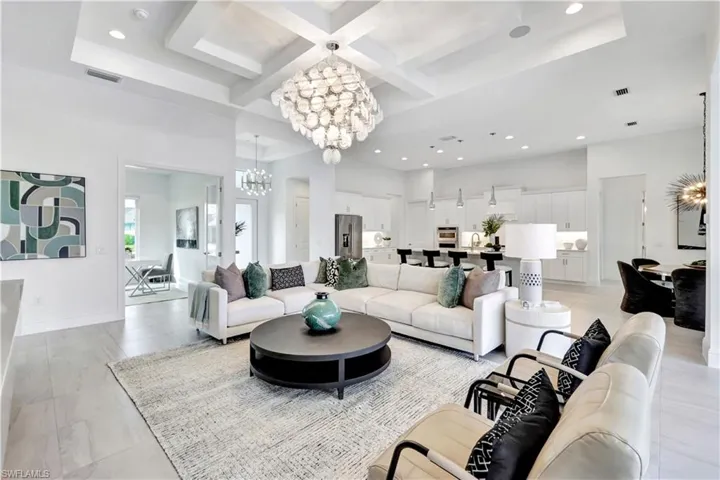 Living area with a chandelier, coffered ceiling, beam ceiling, recessed lighting, and light tile patterned floors