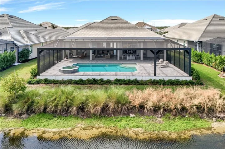 View of pool featuring a sunroom, a patio, a lanai, a pool with connected hot tub, and a lawn
