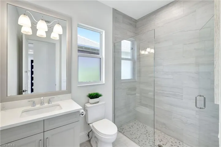 Bathroom featuring a stall shower, vanity, and a chandelier