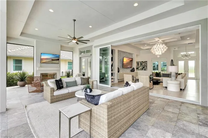 Living room featuring french doors, a glass covered fireplace, healthy amount of natural light, a tray ceiling, and recessed lighting