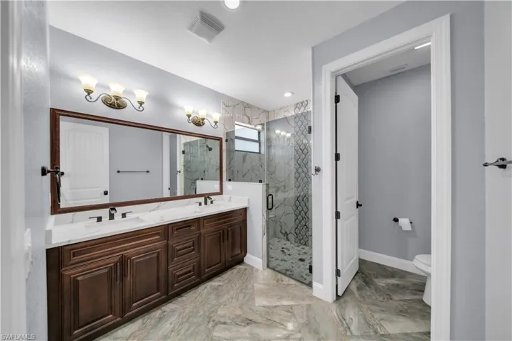 Full bathroom with a marble finish shower, a sink, marble finish floor, and visible vents