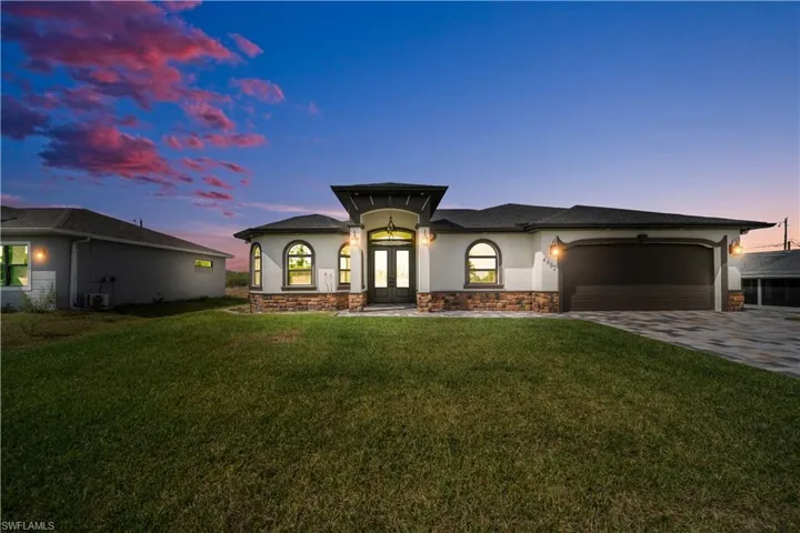 View of front facade featuring concrete driveway, stucco siding, french doors, a front yard, and a garage