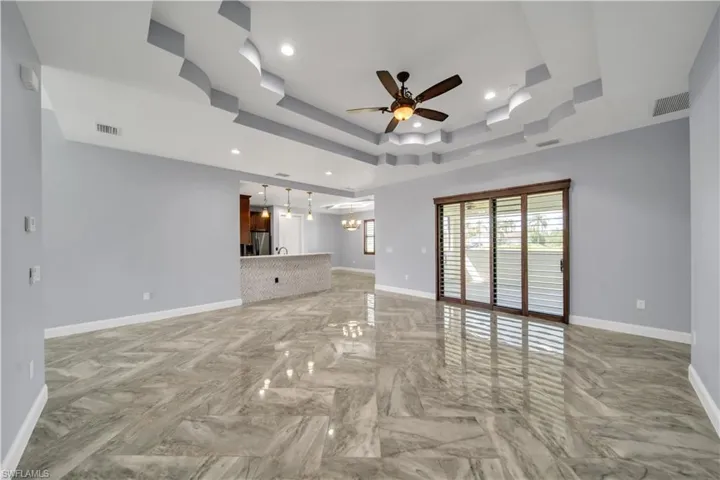 Unfurnished living room featuring a ceiling fan, visible vents, and baseboards